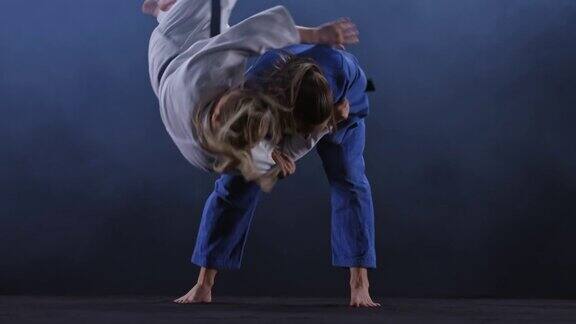 SLOMOLD女柔道运动员在蓝色的服装扔她的对手在地板上