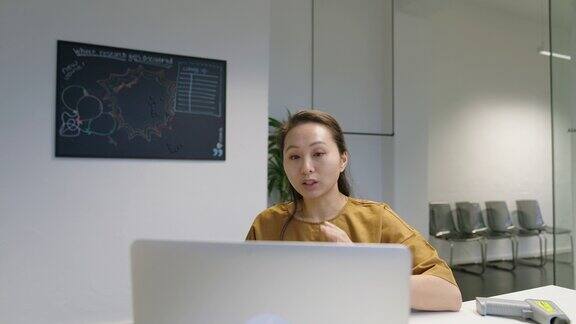 一位年轻女士在办公室用笔记本电脑进行视频通话