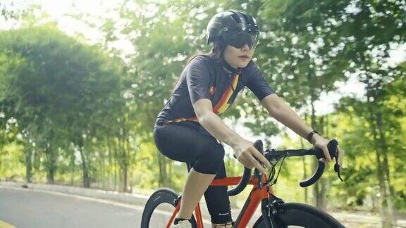 字体查看慢动作亚洲女子橙色自行车戴着防护头盔锻炼训练骑在公园里的自行车