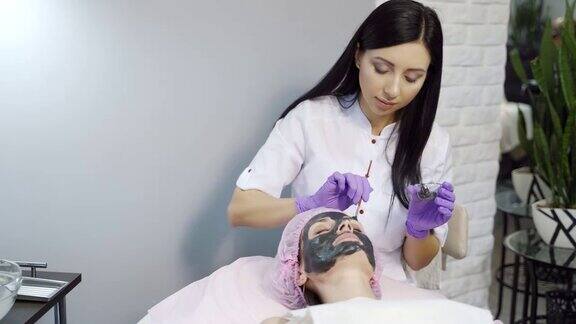 在美容院为年轻女子做面部护理
