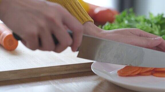 用锋利的刀在木板上切胡萝卜的特写镜头