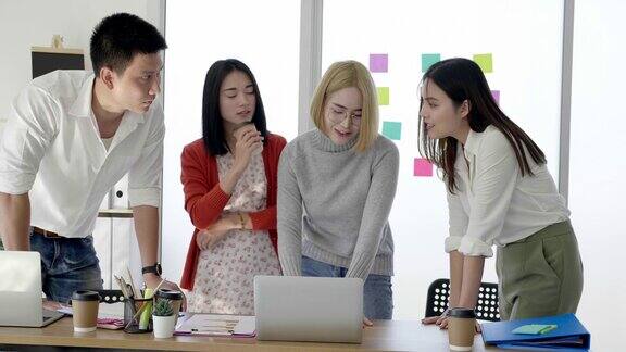 一群年轻的亚洲商人站在办公室里讨论工作演示团队领导用笔记本电脑解释实现目标的策略工作积极思考蒙太奇