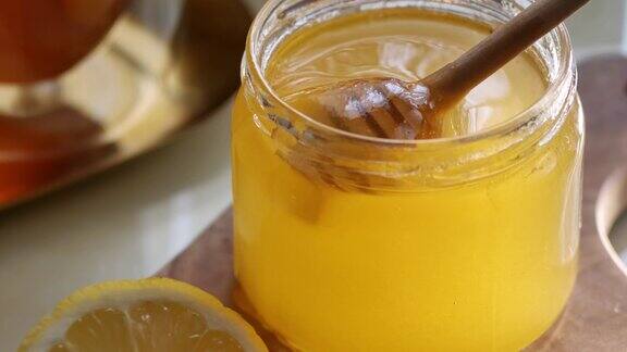 近距离观察蜂蜜从桌上的木勺流出还有茶和柠檬