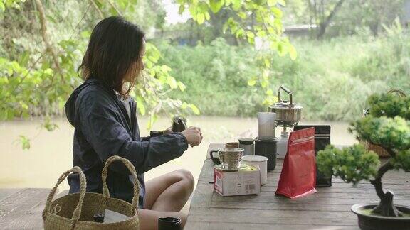 年轻女子坐在外面她准备在木桌上煮咖啡