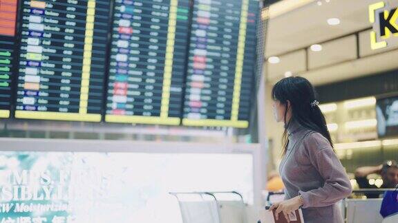 在机场候机楼一名女旅客看表查看航班时刻表她的航班延误了
