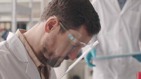 男性科学家在实验室的培养皿中检查物质