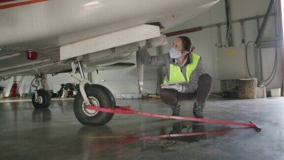 飞机工程师在飞机库里检查飞机引擎然后把它放回飞行
