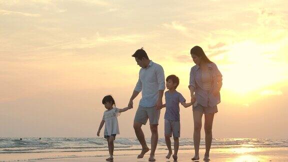 快乐的亚洲家庭漫步在夏日日落的海滩上缓慢的运动家庭假期和旅游