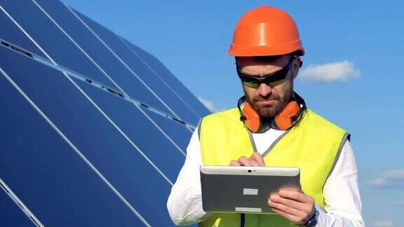 一位男工程师正看着一块太阳能电池板注意到他电脑里的一些东西