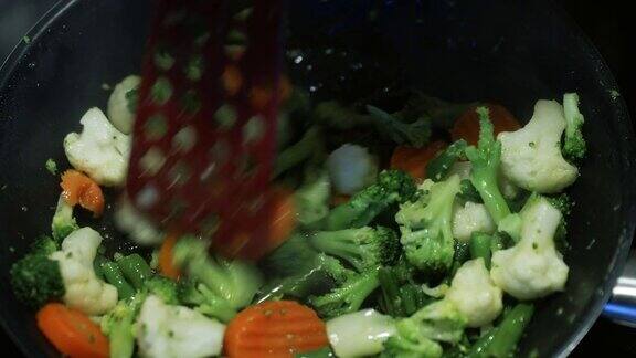 烹饪一个新鲜切好的蔬菜在煎锅上煎胡萝卜花椰菜花椰菜扁豆打开一个煎锅盖