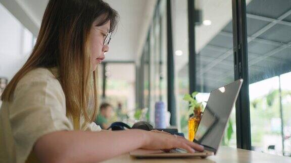 年轻的亚洲少女在当地的一个联合办公场所做电脑作业
