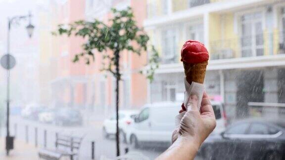 大雨中一个人的手拿着华夫蛋筒和冰淇淋背景是街道