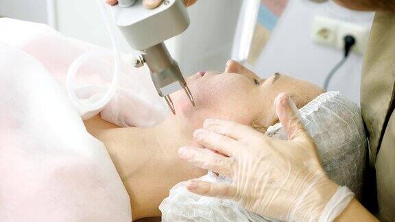治疗师在病人脸上做激光脱毛手术