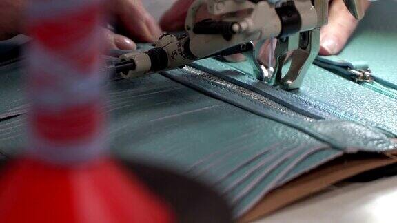 女性双手在缝纫机上把拉链整齐地缝到皮片上概念生产皮具
