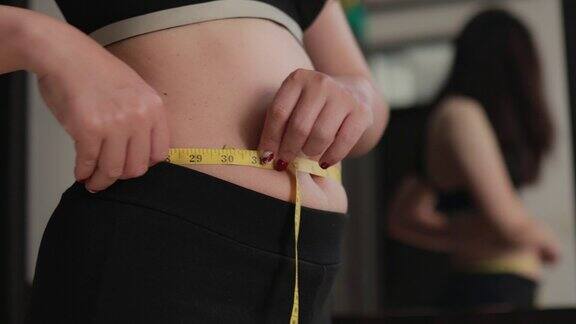 超重的女人用卷尺测量她的胖肚子超重的胖肚子的女人胖女人胖女孩女人减肥的生活方式概念
