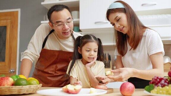 亚洲家庭帮忙做饭和妈妈一起在厨房剥苹果家庭关系概念