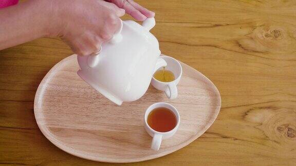 女子从茶壶倒进木桌上的茶杯中茶道概念