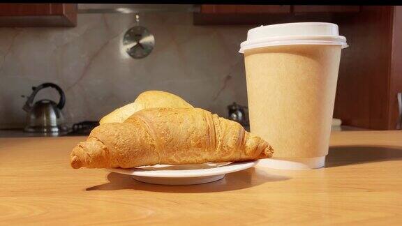 在厨房的桌子上旋转着牛角面包和纸咖啡杯