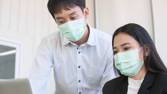 新冠肺炎疫情期间在办公室戴口罩工作的商务人士新常态概念