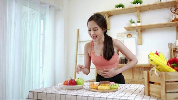 亚洲运动女性正在选择健康的食物而不是厨房里的垃圾食品饮食与健康食品理念