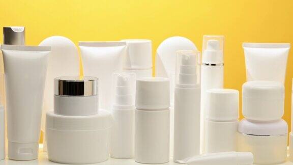 罐子瓶子和空白色塑料管的化妆品在黄色的背景包装霜凝胶血清广告