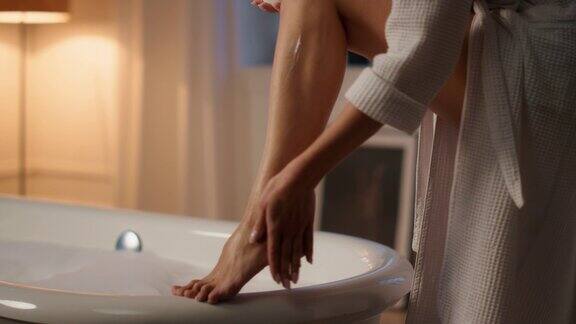 修身模特保湿腿浴室特写不知名的女士正在涂护肤液