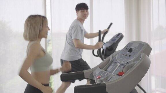 年轻女子在家里或健身房跑步机上跑步年轻男子和他的妻子在跑步机上跑步镜头从女人切换到男人健康生活理念