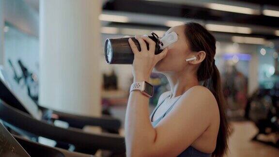 在健身房喝高蛋白奶昔的女运动员
