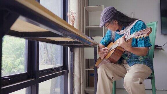 亚洲老年人喜欢在家里的客厅里弹吉他