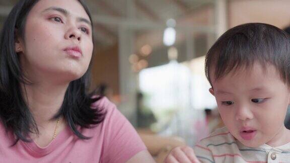 亚洲男婴与母亲在餐厅用餐