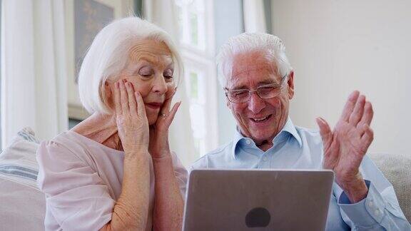 一对老年夫妇用笔记本电脑与家人进行视频通话