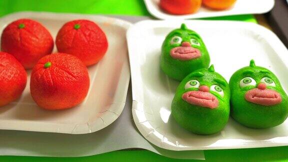 两个用杏仁糖装饰成绿色脸和橙子的盘子
