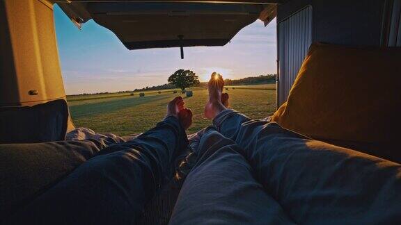 一个阳光明媚的日子一对夫妻躺在草地上一辆露营车的小屋里