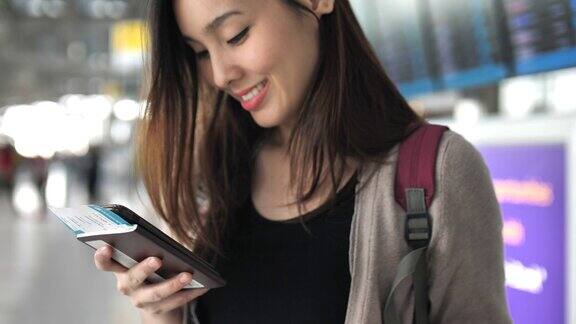亚洲年轻女子使用智能手机与护照在机场旅行