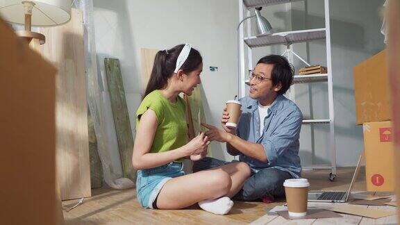 亚洲开朗的年轻夫妇在新居休息时坐在家中装修配件间喝咖啡新家搬迁装修室内概念幸福夫妇讨论