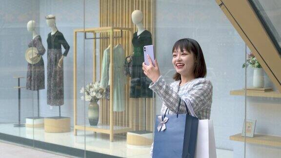 亚洲年轻女子购物后在城市街道上使用智能手机