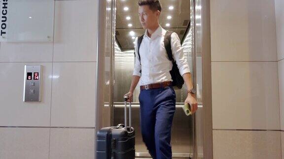 电梯旅行和一个商务亚洲人在机场检查他的航班起飞的时间门地板和迟到的一个男性员工在旅行时提着行李箱