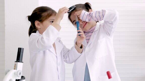 穿着实验服在试管中混合化学物质做科学实验的小学女生在教室里使用显微镜的学生在实验室里用化学流体做研究的学生