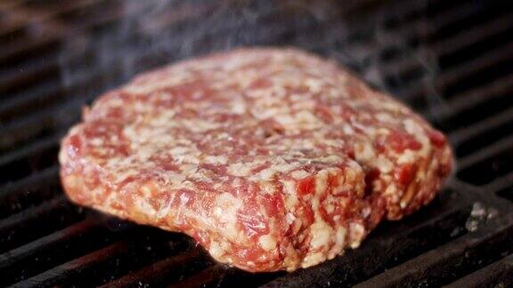 慢动作的牛肉汉堡在烧烤在近距离与火焰和烟雾