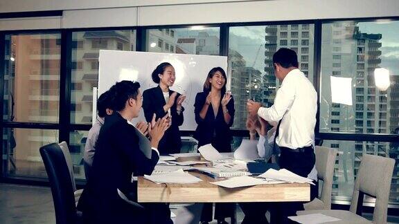 成功的亚洲商人在小组会议上庆祝项目成功