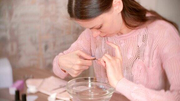 女人用镊子剪表皮使自己修指甲美甲工具放在桌子上