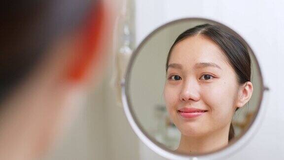 年轻美丽的亚洲女人看着镜子里的自己