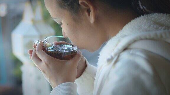 亚洲女性享受热茶的香味喝热茶从玻璃在客厅在早上的时间放松在家