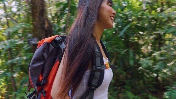 亚洲年轻美丽的女人背包客独自在森林野外旅行迷人的女孩旅行者环顾四周探索而走在自然森林与幸福和乐趣的假期旅行