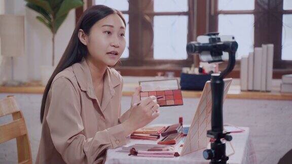 年轻女性作为化妆师使用智能手机拍摄视频博客内容