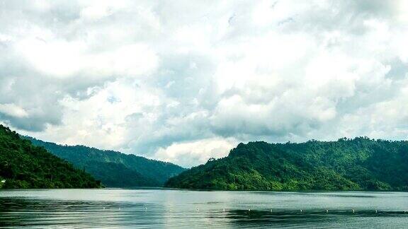 宁静的湖景和移动的云与绿色的山背景