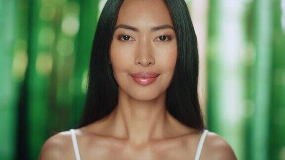 美丽的亚洲女人看着相机微笑女性享受她的美丽高自尊健康有机化妆品护肤品肖像画与抽象的绿色森林自然背景