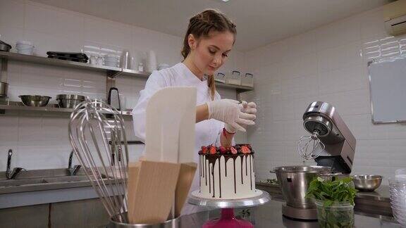 糕点师用巧克力和草莓装饰奶油蛋糕的特写镜头