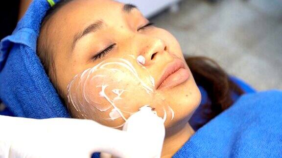 抗衰老面部护理与霜按摩在女人的脸上