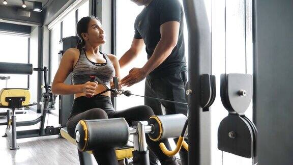 亚洲妇女与教练在健身房锻炼